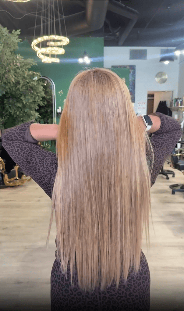 Back view of long blonde hair falling straight and frizz-free after a keratin smoothing treatment at Bellisimo Salon & Boutique